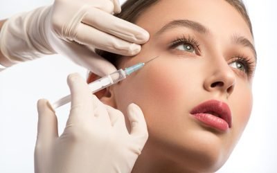 Cute girl receiving hyaluronic acid treatment Serine young woman is getting facial botox injection. Beautician hands in gloves holding syringe near her face